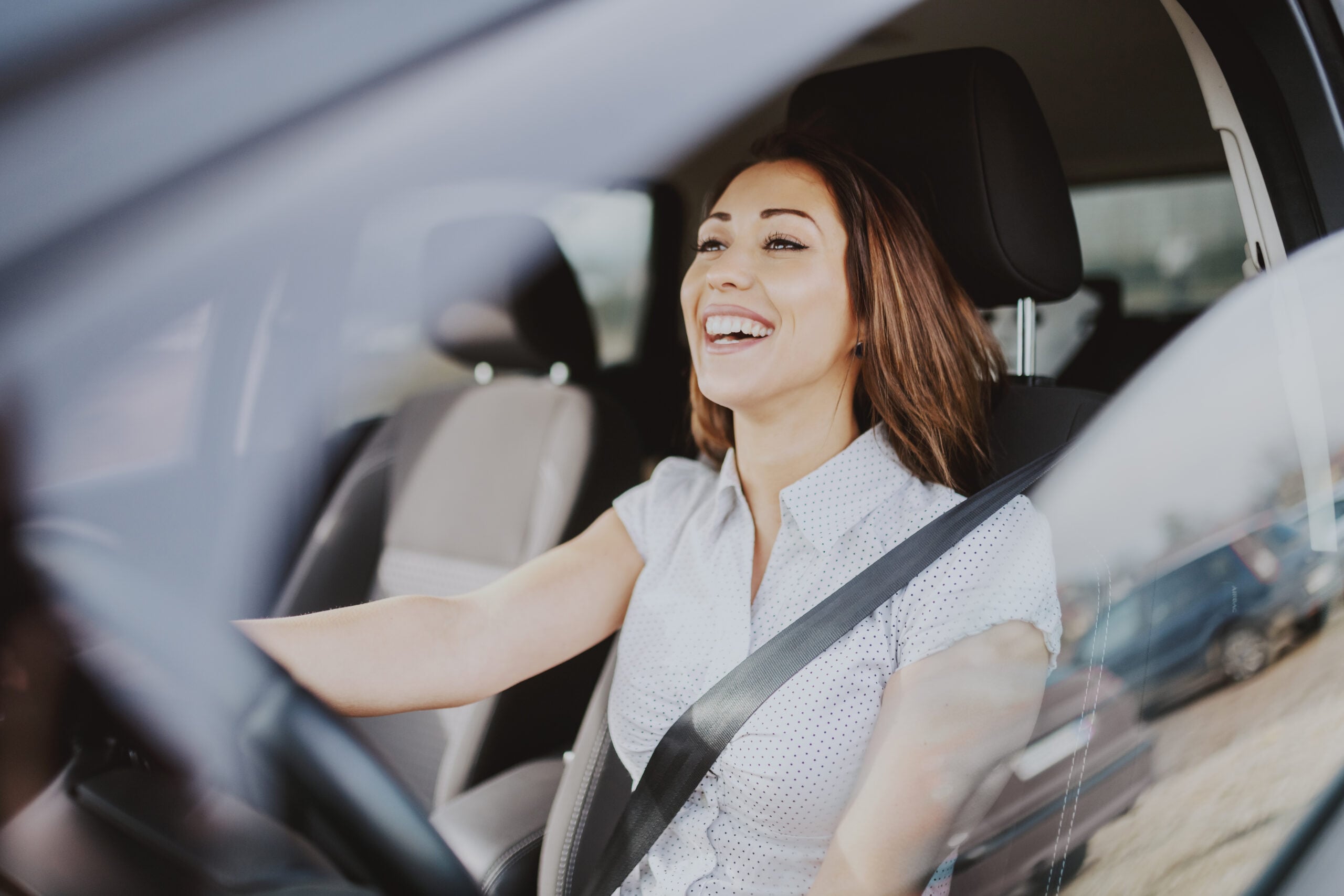 Gorgeous smiling Caucasian brunette driving her car